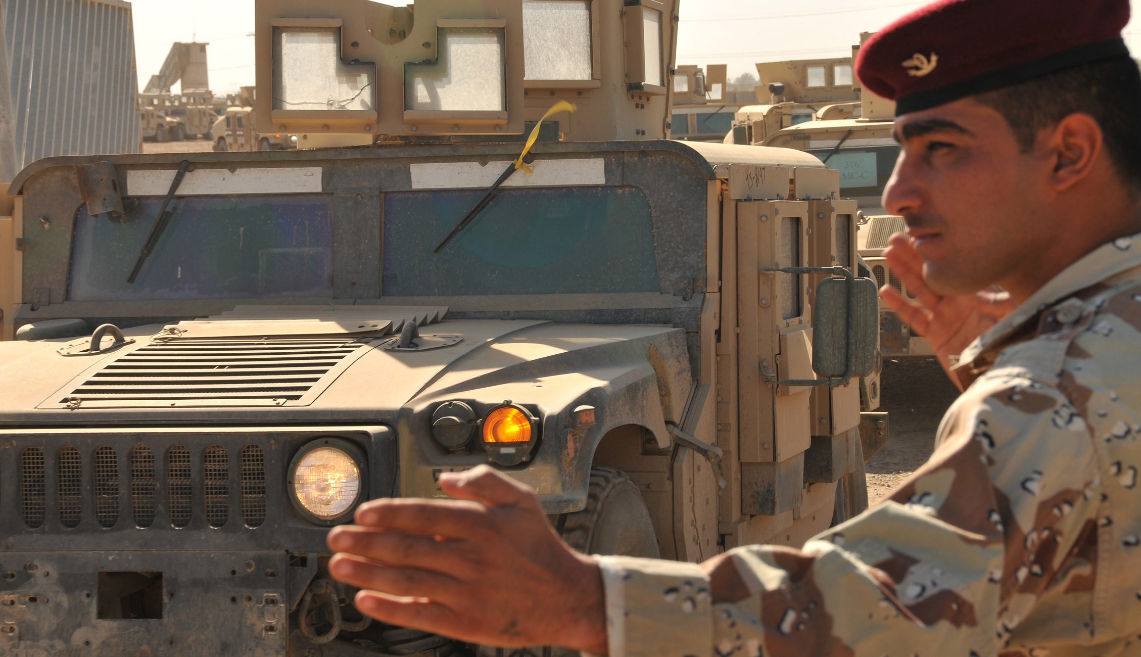 CAMP TAJI, Iraq - Hakem, an Iraqi Army private, directs U.S. and IA Soldiers as they drive M1114 HMMWVs from the Taji Redistribution Property Assistance Team HMMWV yard here recently to the next staging point on the Iraqi part of the camp. The RPAT works with Multi-National Security Transition Command  Iraq to turn over up-armored HMMWVs that will be sold to the Iraqi government for use by IA and Iraqi Police. (U.S. Air Force photo/Staff Sgt. Dilia Ayala)