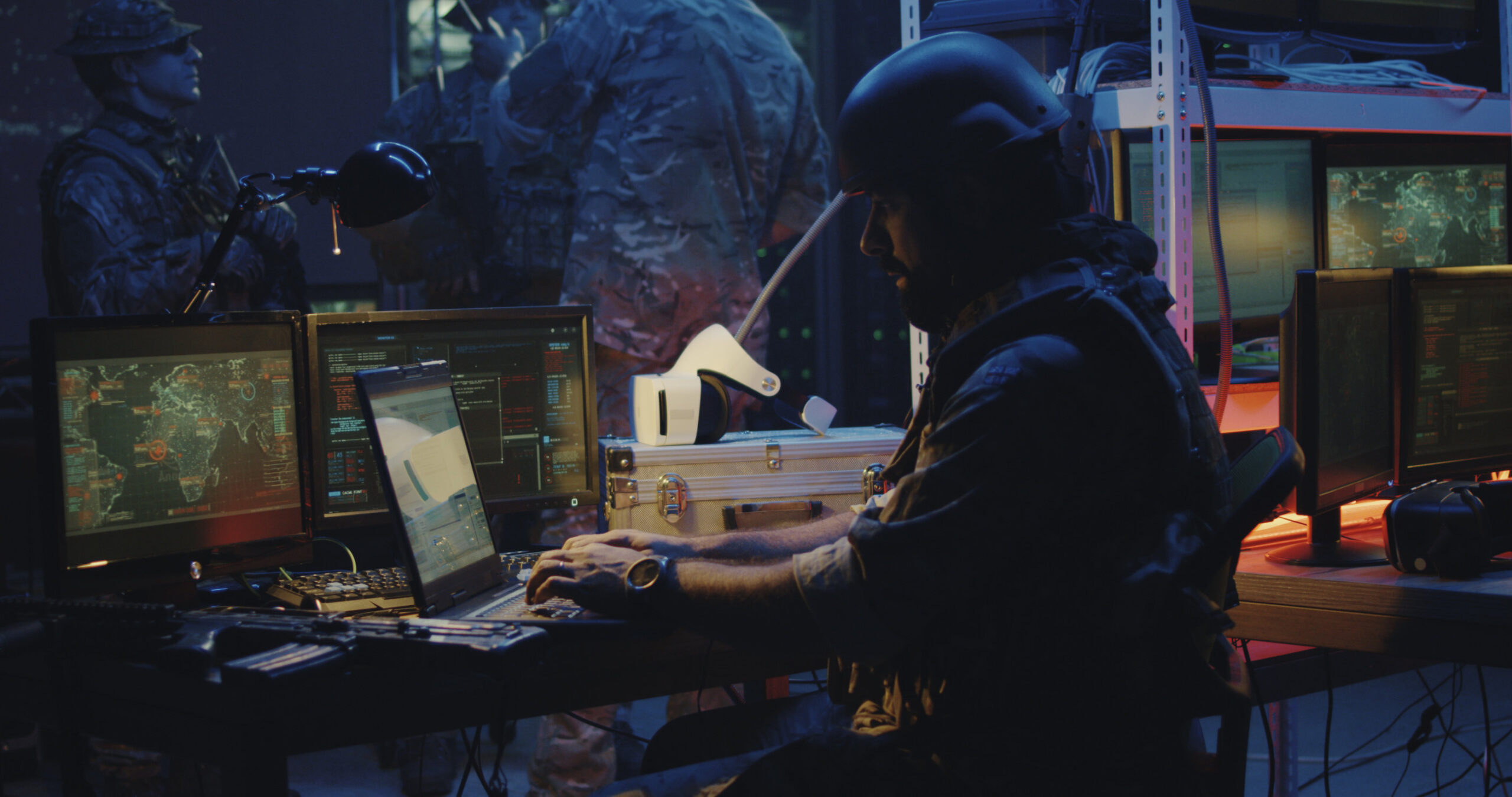 Medium shot of a soldier working on a laptop in full combat gear