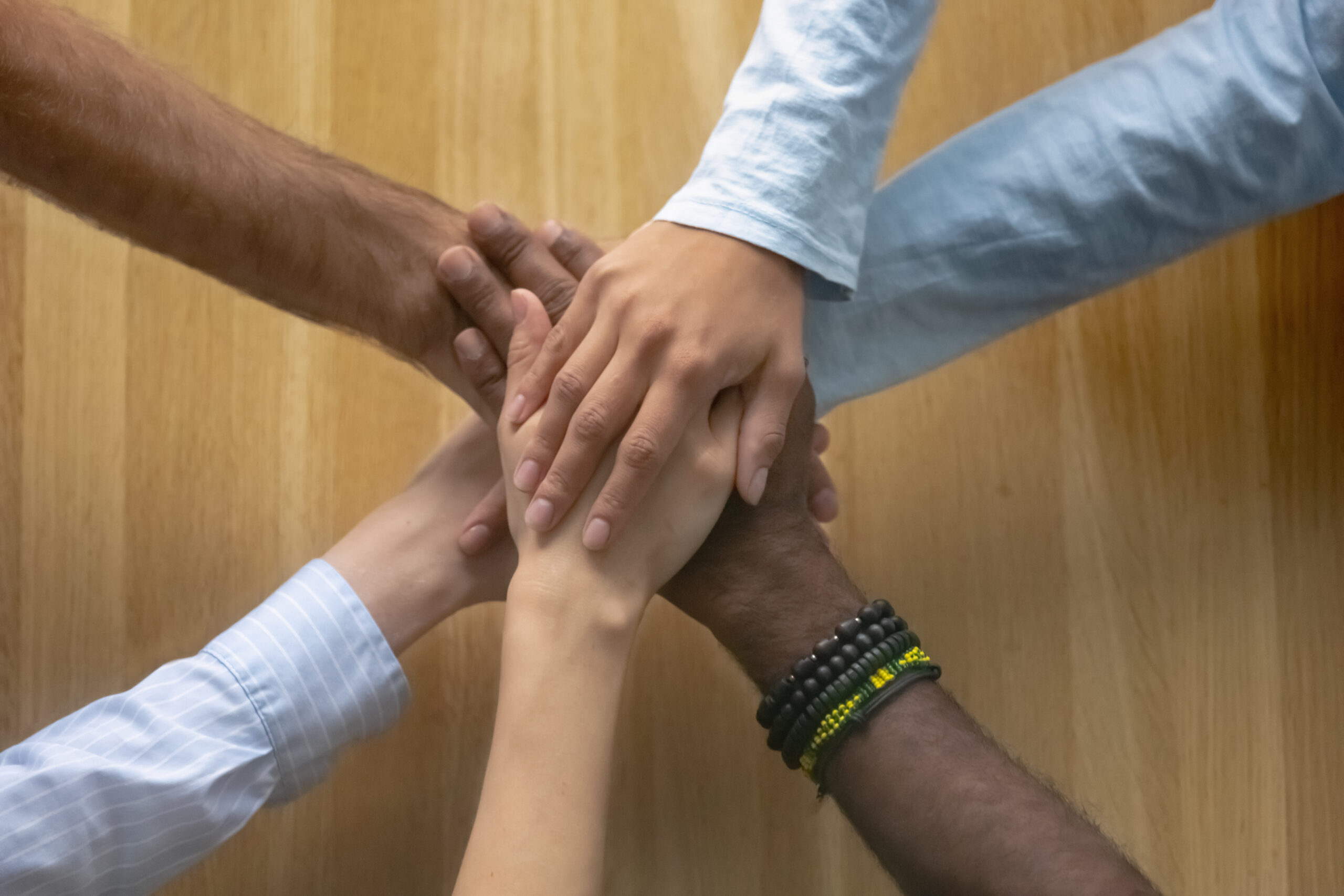 Multi ethnic reliable team business people stack hands as teamwork concept, success and support in group corporate work, shared responsibility loyalty, unity trust in partnership, top close up view